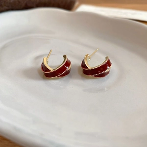 Détail macro de boucles d'oreilles en émail bordeaux avec bordure perlée dorée vintage