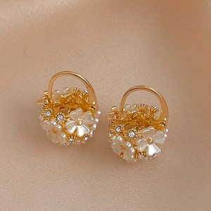 Macro shot of gold floral hoop earrings with white petals and crystals on silk fabric