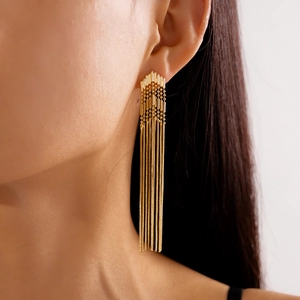 Close-up of golden multi-layered fringe earrings with metallic bead chain design on model