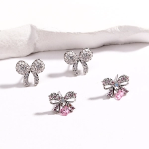 Detail of silver bow earrings with sparkling clear crystals and pink oval gemstones