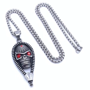 Detailed shot of silver skull pendant featuring red gemstone eyes and zipper element