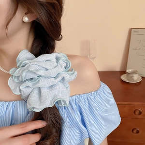 Macro detail of oversized light blue pleated hair scrunchie with green wavy edges