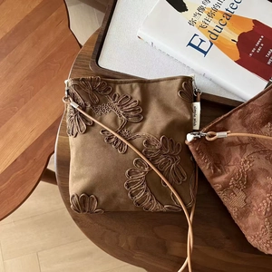 Détail de la broderie florale sur le sac bandoulière vintage en suédine de couleur camel