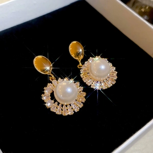 Detailed macro view of 18k gold plated pearl earrings with sparkling diamond halo