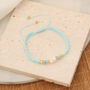 Detailed close-up of light blue seed bead bracelet with golden accents on stone