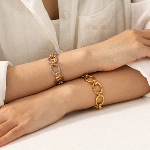 Bracelets bicolores en or et argent portés par un mannequin sur une table blanche