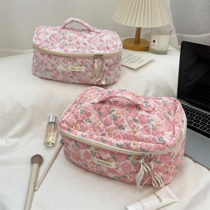 Quilted floral makeup bag set with large and small pouches on a cozy desk setup