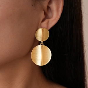 Close-up of golden brushed double circle earrings worn by model showing texture