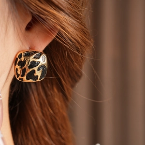 Gros plan de boucles d'oreilles carrées dorées avec motif léopard noir sur un modèle