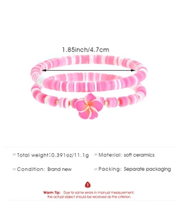 Detalle de pulseras de cuentas de arcilla rosa y blanca con dije de flor y medida
