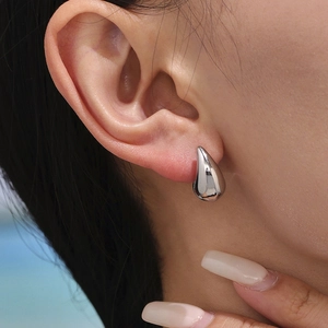 Polished silver teardrop stud earrings in 18K gold plated stainless steel on model