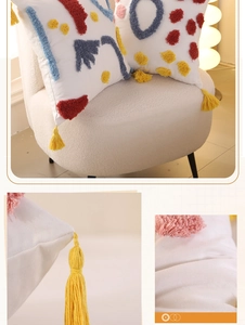 Close-up of colorful tufted rainbow patterns and yellow tassels on a white cotton pillow cover