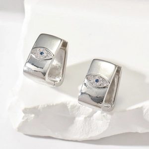 Detailed macro view of silver geometric rectangle earrings with blue evil eye zircon inlay