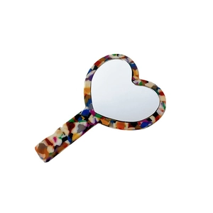 Portable heart-shaped hand mirror with a colorful mosaic acetate frame on a white background