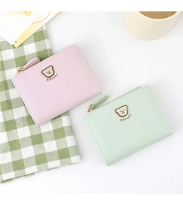 Close-up of pink and mint green small bear wallets with zipper on a plaid background