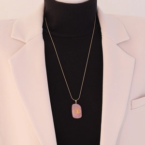 Pink gemstone Tree of Life necklace styled on model with professional blazer outfit