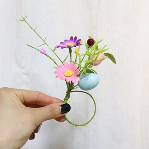 Close-up of handmade Easter napkin ring featuring pastel eggs and daisy flowers