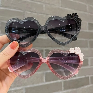 Close-up of kids heart sunglasses with glitter finish and small floral side details