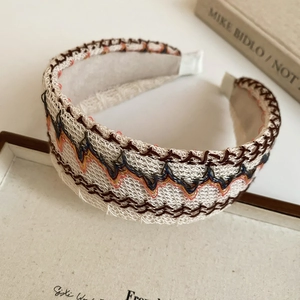 Détail du serre-tête tissé beige avec broderies colorées et texture de style tweed