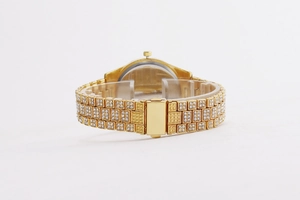 Detail view of gold-tone crystal-encrusted watch strap with a folding clasp back