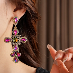 Detail shot of vintage golden cross earrings with colorful rhinestones on model's ear