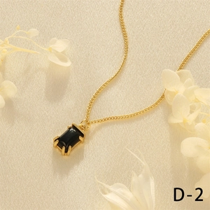 Macro shot of gold fine Cuban necklace with rectangular black gem pendant on white satin
