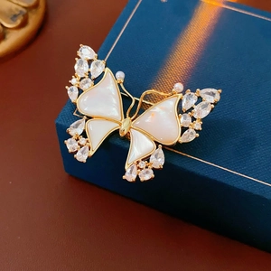 Macro shot of 18k gold butterfly brooch with white shell wings and pearl accents