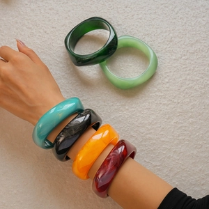 Close-up of thick geometric resin bangles with marble texture and polished glossy finish