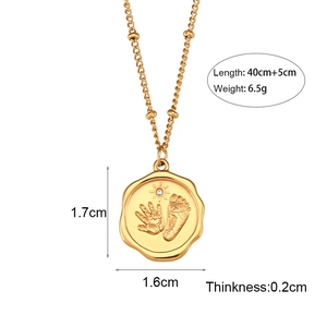 Collier à billes en acier inoxydable doré avec pendentif empreintes de bébé sur fond blanc