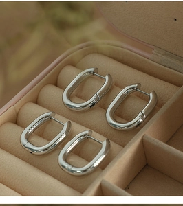 Macro view of two pairs of U-shaped silver titanium steel earrings in a velvet box