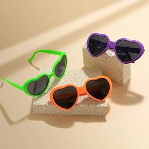 Fashionable heart-shaped sunglasses in green, orange, and purple on stone decor