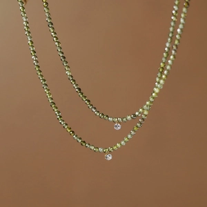 Detail of double-layer necklace with olive green beads and sparkling white zircon pendants