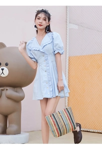 Detailed view of light blue dress with ruffled collar and puff sleeves on a model outdoors