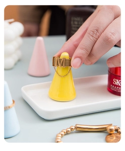 Detail view of a gold letter M ring with mesh band on a yellow ceramic cone stand