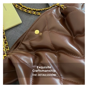 Macro detail of dark brown quilted leather bucket bag with golden chain and metallic rivets