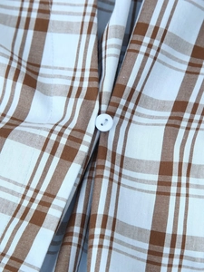 Close-up of brown and white checkered poplin fabric with a single white button detail