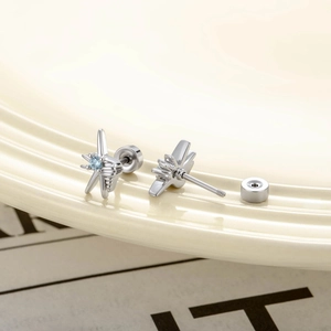Silver starfish stud earrings with blue cubic zirconia on a beige wavy display tray