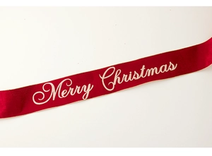 Close-up of red Christmas ribbon with golden Merry Christmas lettering and stitched edges