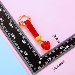 Macro shot of red rhinestone strawberry keychain with gold hardware and size dimensions