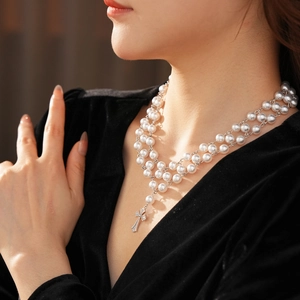 Detail of double-layer pearl necklace with a silver cross pendant on a model