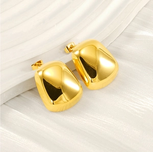 Macro shot of chunky gold titanium steel stud earrings on a textured stone display