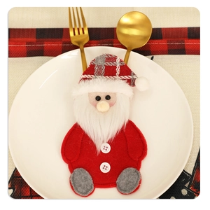 Detail of Santa Claus felt cutlery holder on a white plate with gold utensils
