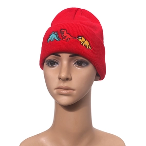 Vibrant red knit beanie featuring colorful cartoon dinosaur embroidery for winter warmth