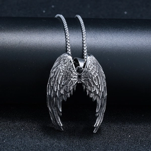 Détail du collier avec pendentif aile d'ange vintage argenté sur un support noir