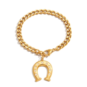 Detail of gold Cuban link bracelet with a sparkling rhinestone horseshoe pendant