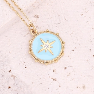 Gold stainless steel starburst pendant necklace with light blue enamel on stone background