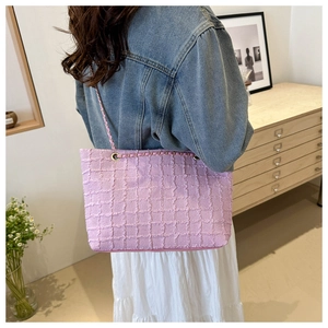 Borsa tote rosa testurizzata con tracolla a catena indossata da una modella