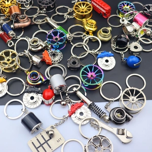 Collection of metal automotive parts keychains including turbo, rims, and helmets