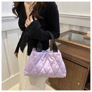 Purple quilted puffer handbag featuring a padded lattice texture and black woven handles