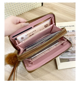 Close-up of brown long wallet with pink lining and multiple card slots on wooden table